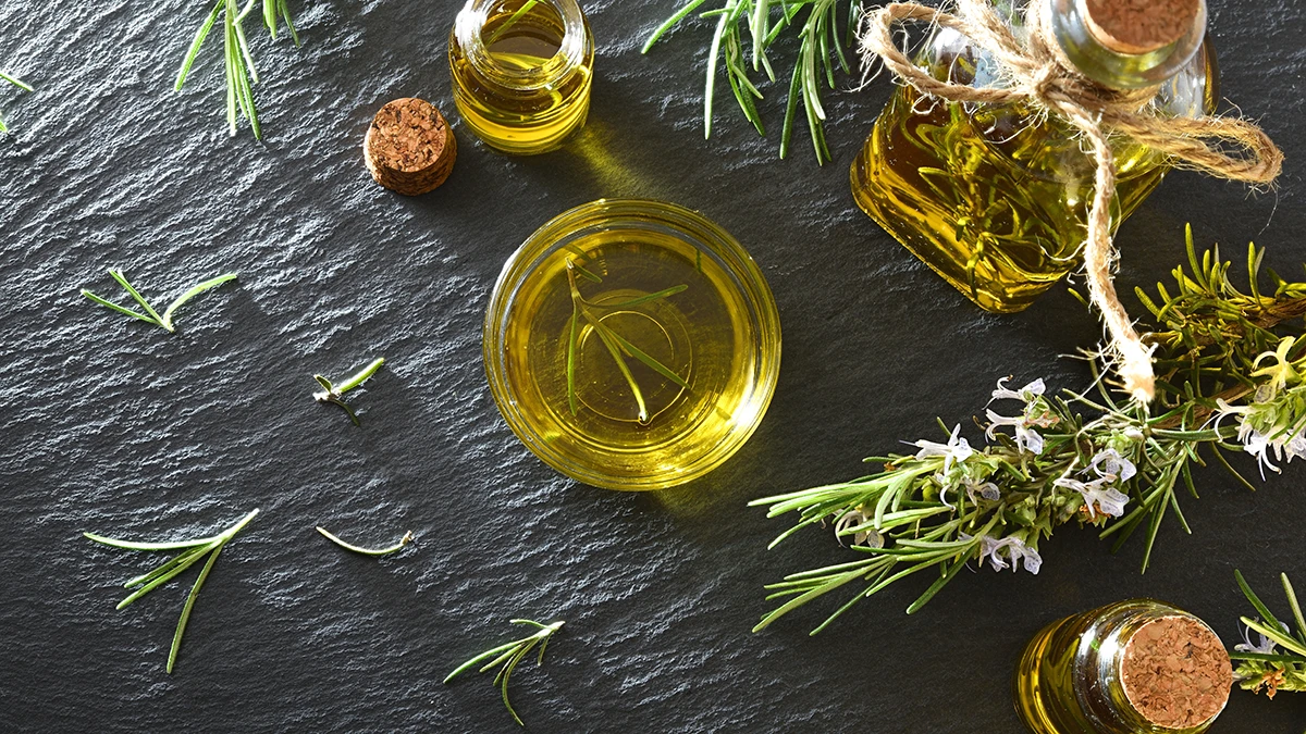 rosemary oil for hair and rosemary on a dark stone table